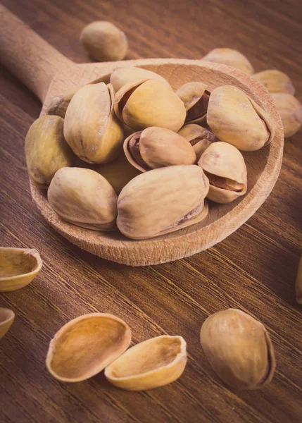 Zdjęcia archiwalne, orzechy pistacjowe z łyżką na drewnianym stole, zdrowe jedzenie — Zdjęcie stockowe