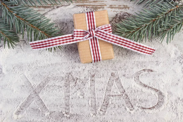 Inskriften xmas skriven på mjöl på degen för pepparkakor, gåva och Gran grenar — Stockfoto