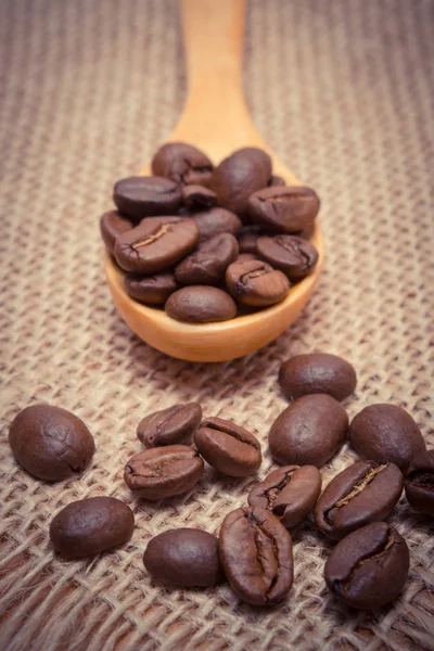 Vintage photo, Heap of coffee beans with wooden spoon on jute canvas — Stock Photo, Image