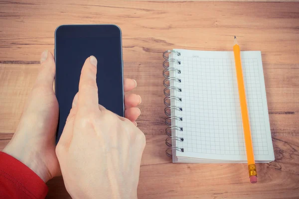 Vintage photo, Hand of woman using mobile phone, notepad for writing notes — Stock Photo, Image