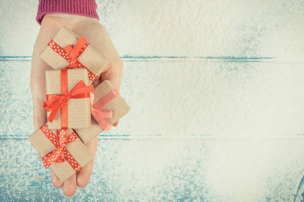 Рука женщины с подарками на Рождество или другой праздник на снежном фоне, копия пространства для текста
