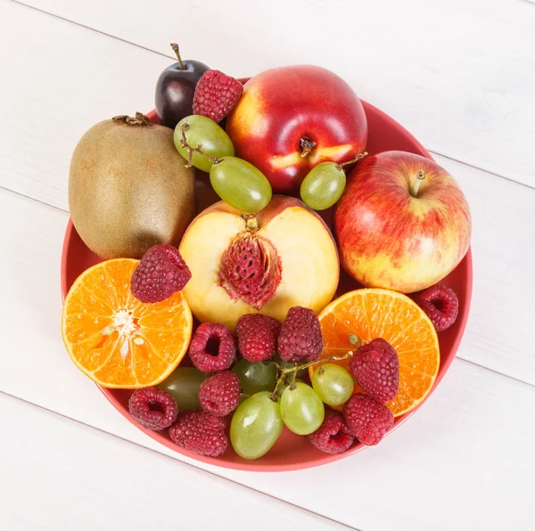 Frutti freschi maturi sul piatto sdraiato su tavole bianche — Foto Stock