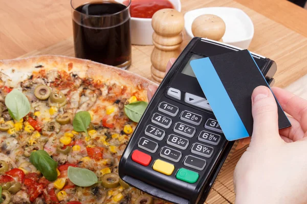 Использование платежного терминала с бесконтактной кредитной картой для оплаты в ресторане, финансовая концепция, вегетарианская пицца — стоковое фото