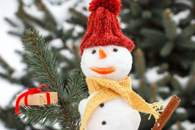 Noel için hediye ile dekore edilmiş kardan adam, iğne yapraklı ağaç arka plan kar kaplı.