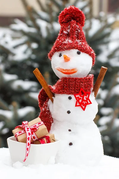 Schneemann dekoriert mit Geschenken für Weihnachten oder Valentinstag auf dem Hintergrund des Nadelbaums bedeckt Schnee — Stockfoto