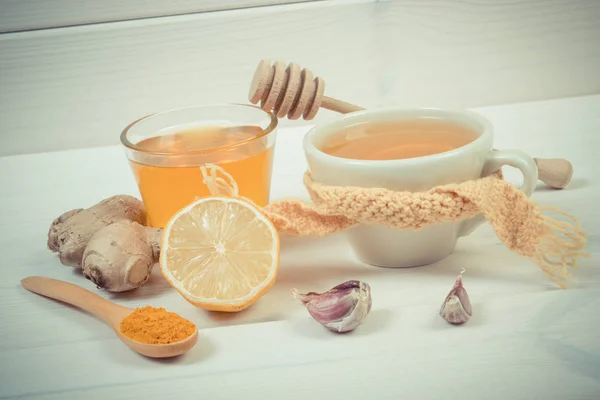 Винтажное фото, чашка чая с лимоном и ингредиенты для приготовления согревающего напитка — стоковое фото