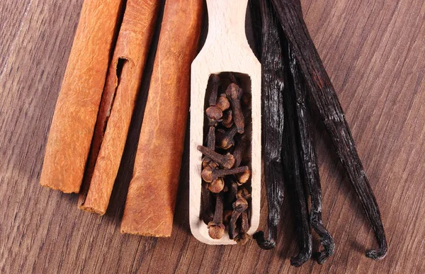 Nahaufnahme von Gewürznelken, duftender Vanille und Zimt auf Holzplanke — Stockfoto