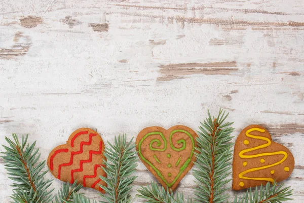 Pão de gengibre decorado fresco assado e ramos de abeto no fundo de madeira velho, tempo de Natal — Fotografia de Stock