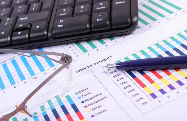 Pero, brýle a počítače klávesnice na grafu finanční, obchodní koncept — Stock fotografie