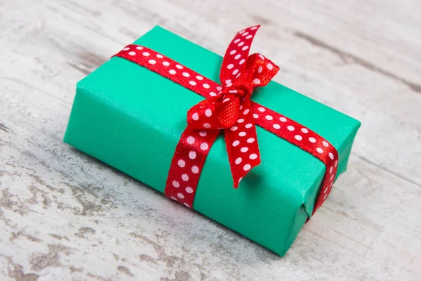 Green gift for Christmas or other celebration on wooden plank — Stock Photo, Image