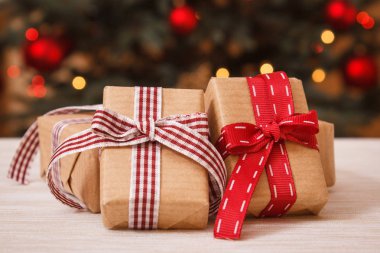 Sarılmış hediyeler ve arka planda ışıkları ile Noel ağacı