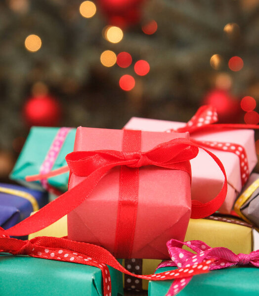 Красочные завернутые подарки и елка с огнями на заднем плане
