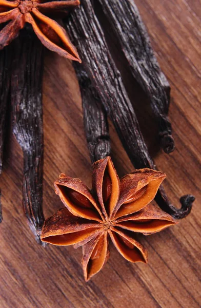 Closeup de anis estrelado e baunilha perfumada na prancha de superfície de madeira — Fotografia de Stock