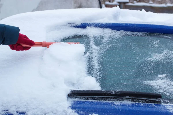 Ręka kobiety za pomocą pędzla i usunąć śnieg z samochodu i szyby — Zdjęcie stockowe