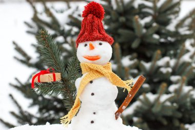 Noel için hediye ile dekore edilmiş kardan adam, iğne yapraklı ağaç arka plan kar kaplı.