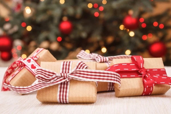 Загорнуті подарунки та різдвяна ялинка з вогнями на фоні — стокове фото