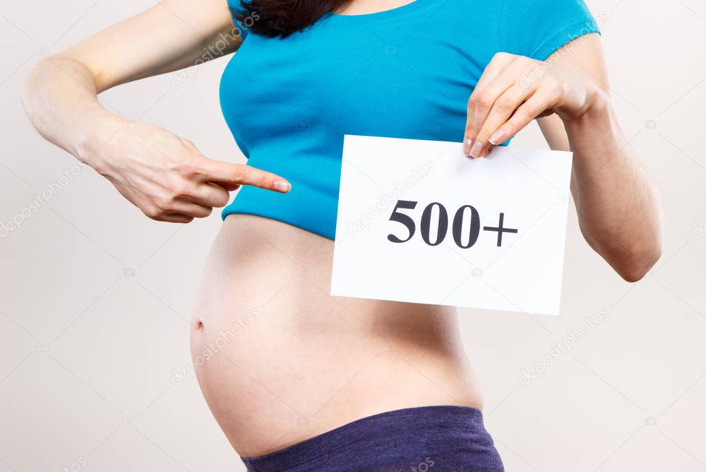 Pregnant woman showing card with inscription 500+, social program and policy in Poland