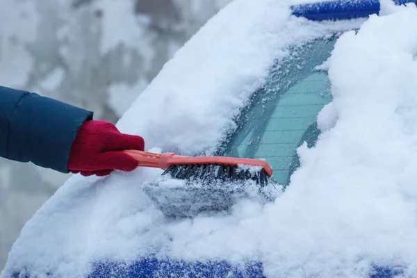 Mano della donna con pennello e rimuovere la neve da auto e parabrezza — Foto Stock