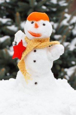 Kardan adam eşarp ve mandalina kabuğu, iğne yapraklı ağaç kaplı kar arka plan ile dekore edilmiş