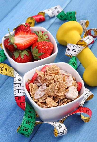 Fresh strawberries, wheat and rye flakes, dumbbells and centimeter, healthy and sporty lifestyle Stock Photo