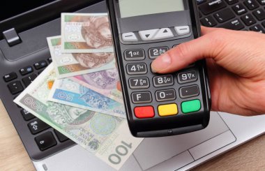 El kullanarak ödeme terminal, kadının Polonya para birimi para üstünde laptop