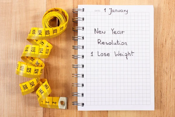 New years resolutions written in notebook and tape measure — Stock Photo, Image