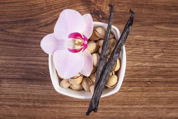 Orzechy pistacjowe, kwitnących orchidei i pachnące laski wanilii, składników kosmetycznych — Zdjęcie stockowe