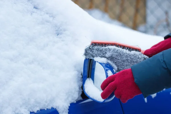 Hand of woman using brush and remove snow from car and mirror — Stock Photo, Image