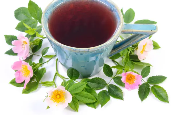 Tasse Tee und wilde Rose Blume auf weißem Hintergrund — Stockfoto