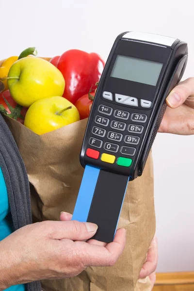 Рука пожилой женщины с помощью платежного терминала с кредитной картой, безналичная оплата покупок — стоковое фото