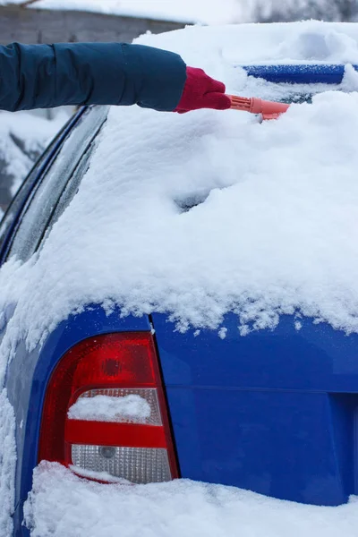 車とフロント ガラスから雪をブラシと削除を使用して女性の手 — ストック写真