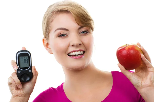 Mulher feliz segurando glicosímetro e maçã fresca, medindo e verificando o nível de açúcar, conceito de diabetes — Fotografia de Stock