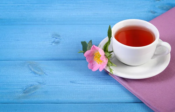 Tasse de thé et fleur de rose sauvage sur des planches bleues, espace de copie pour le texte — Photo
