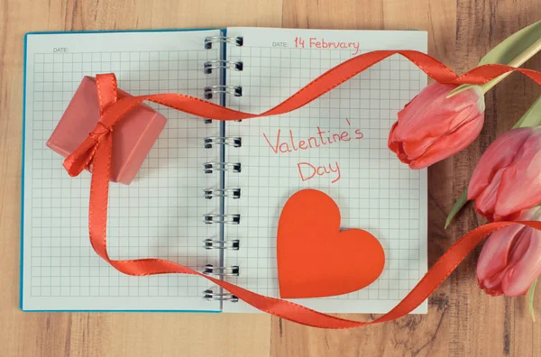 Jahrgangsfoto, Valentinstag in Notizbuch geschrieben, frische Tulpen, verpacktes Geschenk und Herz, Dekoration für Valentinstage — Stockfoto