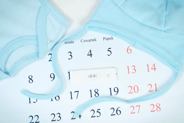 Foto vintage, test di gravidanza con risultato positivo e abbigliamento per neonato sul calendario, in attesa per il bambino — Foto Stock