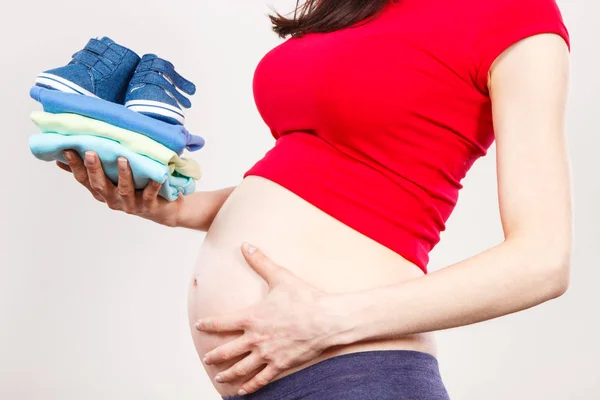 Zwangere vrouw met kleding voor pasgeboren, verwacht voor baby — Stockfoto