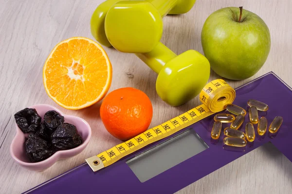 Balança digital com fita métrica, halteres, comprimidos, frutas, conceito de emagrecimento — Fotografia de Stock