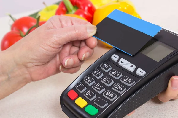 Рука старшої жінки, що використовує платіжний термінал з безконтактною кредитною карткою, платить за покупки — стокове фото