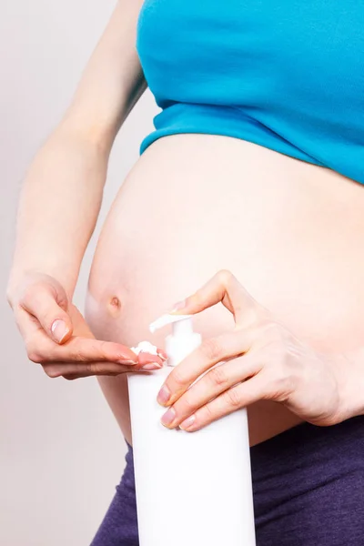 Mujer embarazada aplicando loción hidratante en el vientre, evitar las estrías — Foto de Stock