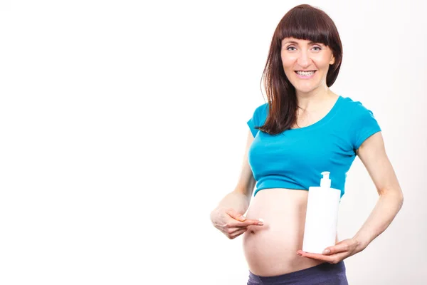 Mujer embarazada aplicando loción hidratante en el vientre, evitar las estrías — Foto de Stock