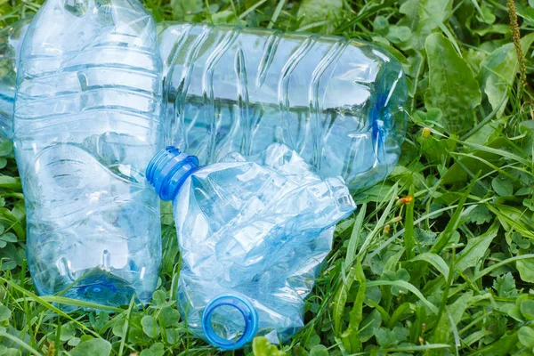 Plastic bottles of mineral water on grass in park, littering of environment — Stock Photo, Image