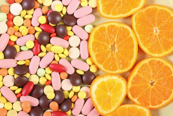 Coloridas píldoras médicas y naranja fresca como fondo, cuidado de la salud y el concepto de estilo de vida saludable — Foto de Stock