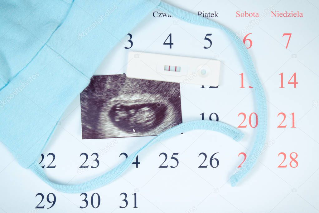Pregnancy test, ultrasound scan of baby and clothing for newborn on calendar, expecting for baby