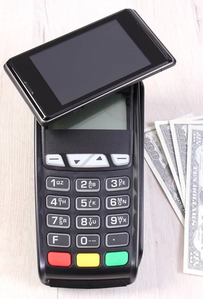 Payment terminal with mobile phone with NFC technology and currencies dollar, cashless paying for shopping or products