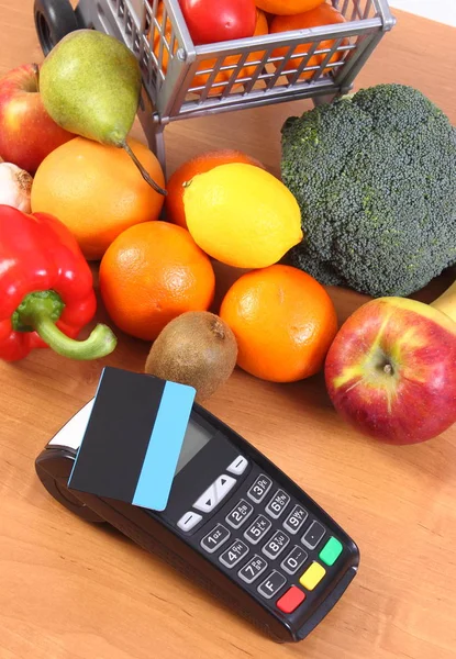 Платежный терминал с бесконтактной кредитной картой, фруктами и овощами, безналичная оплата покупок — стоковое фото