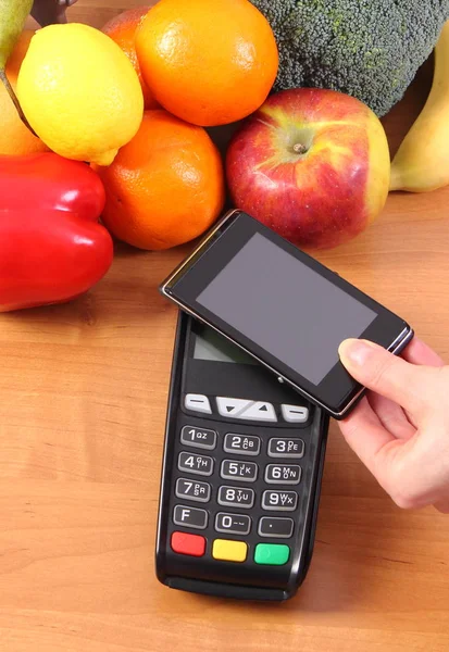 Terminal de pagamento e telefone celular com tecnologia NFC, frutas e legumes, sem dinheiro pagando por compras — Fotografia de Stock