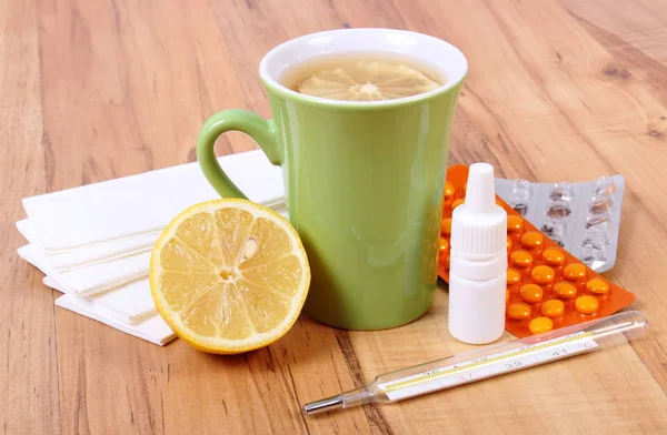 Prášky a nosní kapky při nachlazení, kapesníky a horký čaj s citronem — Stock fotografie