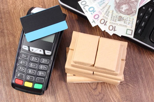 Payment terminal with credit card, polish money, laptop and wrapped boxes on wooden pallet — Stock Photo, Image