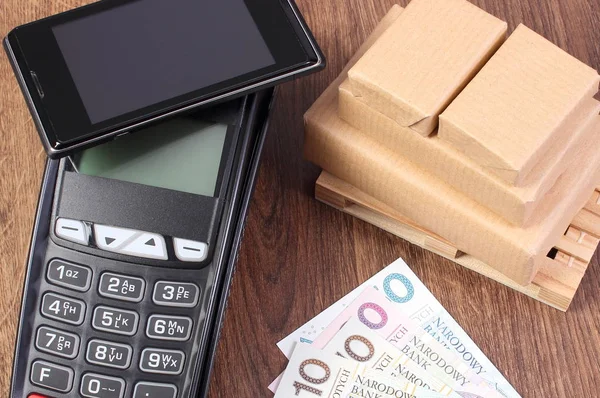 Terminal de pagamento com telefone celular com tecnologia NFC, dinheiro em moeda polonesa e caixas embrulhadas em paletes de madeira — Fotografia de Stock