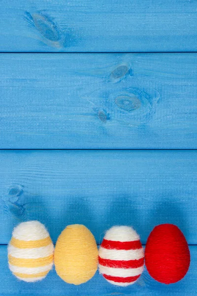 Easter eggs wrapped woolen string on blue wooden boards, copy space for text, decoration for Easter — Stock Photo, Image